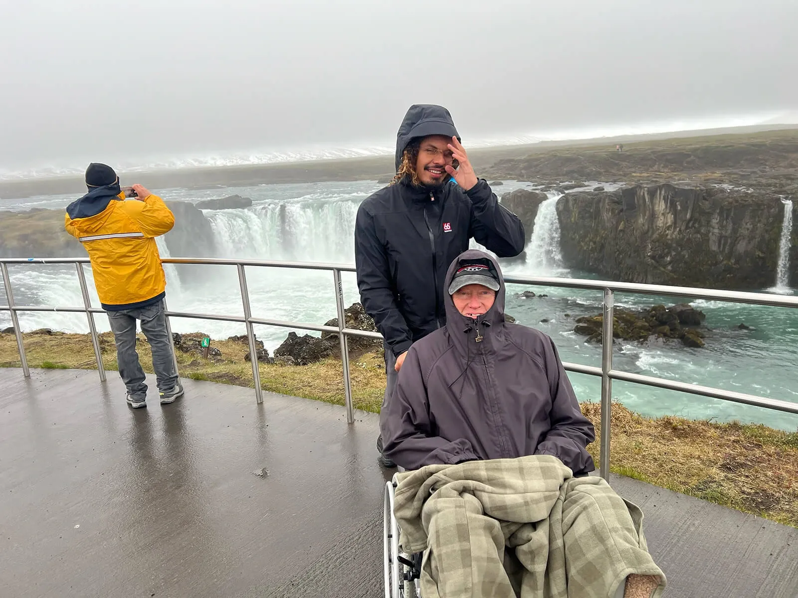Guide assisting a traveller in a wheelchair at Goðafoss waterfall