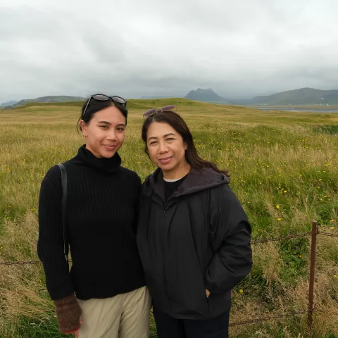 Mother and daughter side by side in a grassy meadow on the South Coast, mountains behind them